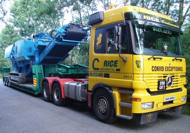 Heavy processing equipment secured behind a Rice tractor unit.